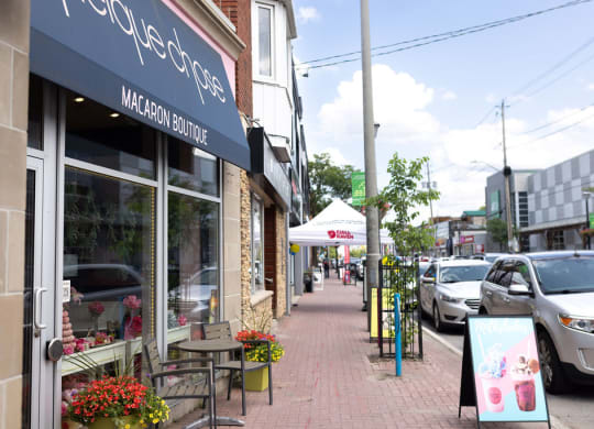 a city street with cars parked on the side of the road and a cafe on the sidewalk