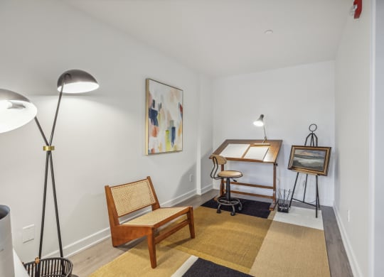 a living room with a desk and chair and a painting on the wall