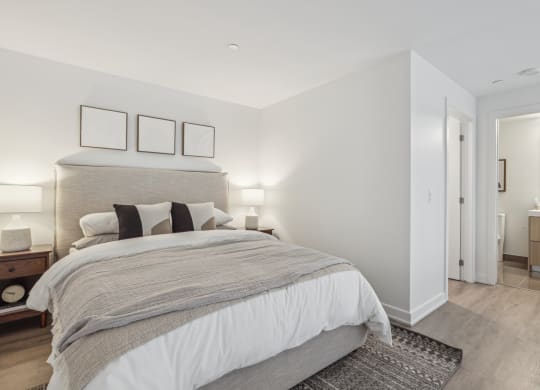 a white bedroom with a large bed and a bathroom