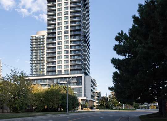 A tall building with many windows stands next to a tree.