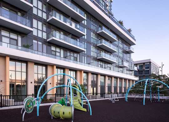 A playground with a slide and swings in front of a tall building.