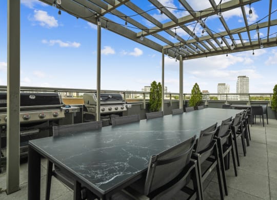 a long communal table on the roof of a building with barbecue grills