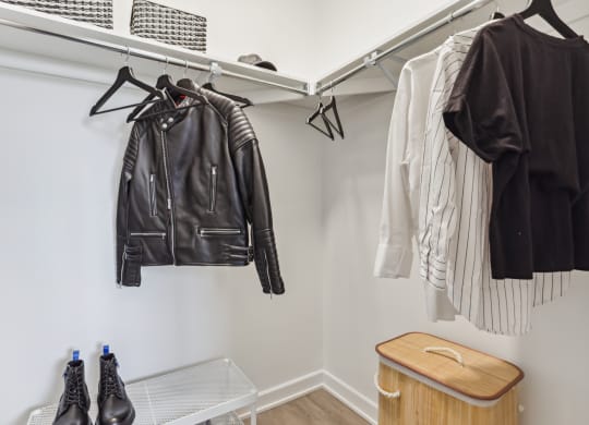 a walk in closet with leather jackets hanging on the wall and shoes on a rack
