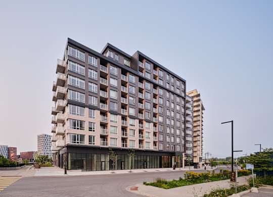 A modern multi-story building with a parking lot in front.