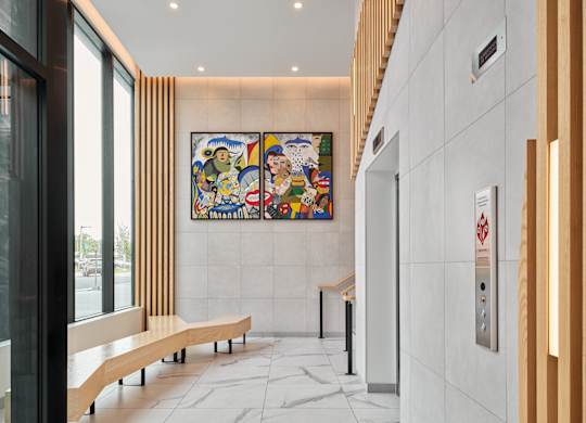 A hallway with a large painting on the wall and wooden benches.