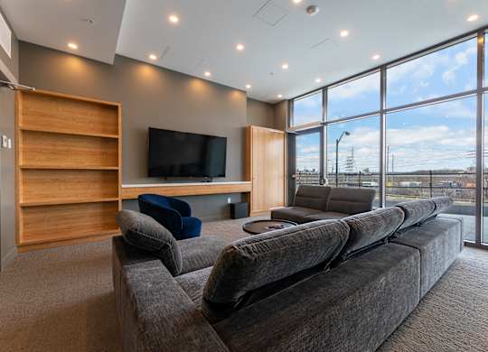 A modern living room with a large grey sofa and a wooden entertainment center.