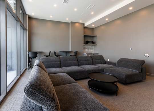 A grey sectional sofa with a black coffee table in front of it.