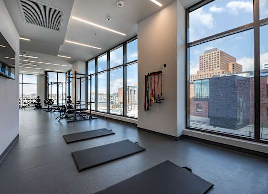 A yoga studio with mats on the floor and a view of the city outside the windows.