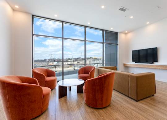 A living room with orange chairs and a flat screen TV.