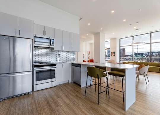 A modern kitchen with stainless steel appliances and wooden flooring.