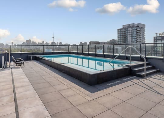 a rooftop swimming pool on the top of a building with a city in the background