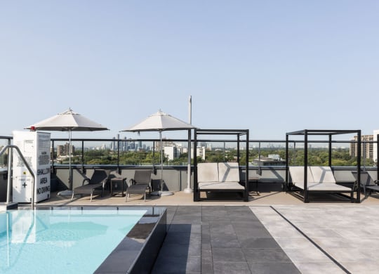 a rooftop pool with lounge chairs and umbrellas