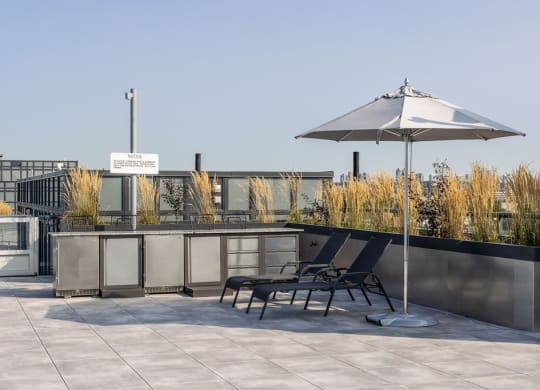 a roof terrace with two lounge chairs and an umbrella