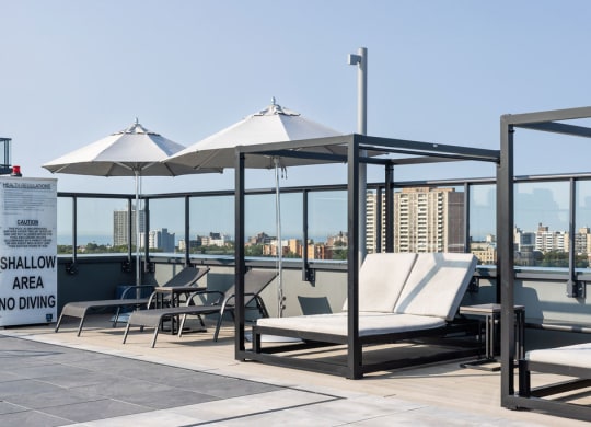a roof top deck with lounge chairs and umbrellas