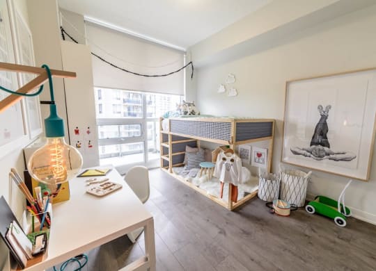 a bedroom with a crib and a desk and a window