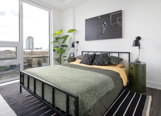 bed with green sheets and painting above headboard