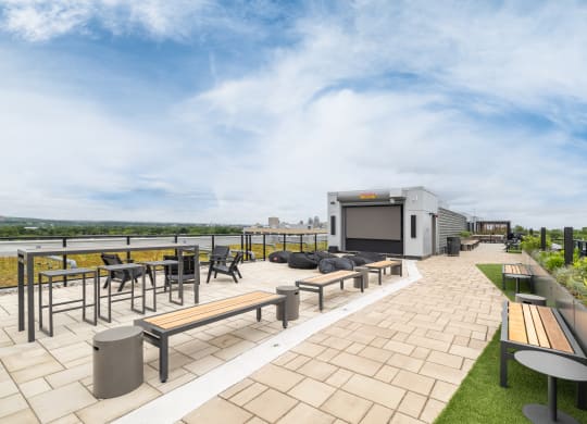 a roof top patio with tables and benches and a movie screen