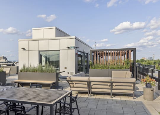 a roof deck with patio furniture and a building in the background