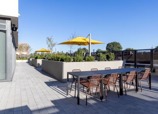 a terrace with a table and chairs with yellow umbrellas in the background