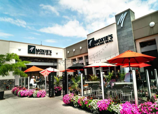 the exterior of a restaurant with tables and umbrellas