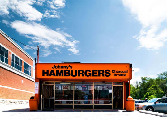 the front of a hamburger shop with a orange sign