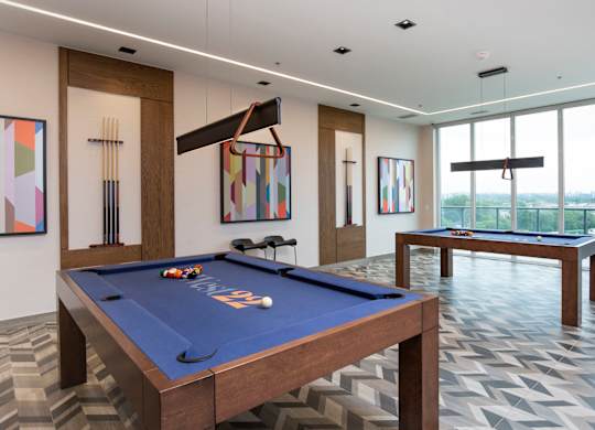 a games room with two pool tables and views of a city