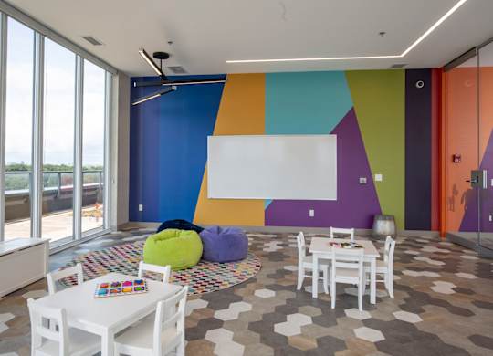 a living room with tables and chairs and a wall with a painting on it
