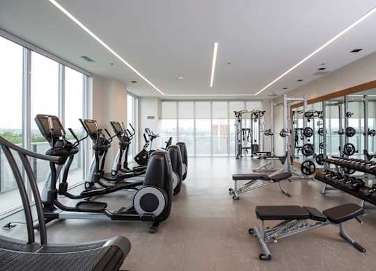 a gym with weights and cardio equipment on the floor and large windows