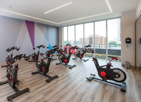 a spin class room with exercise bikes in front of a wall of windows