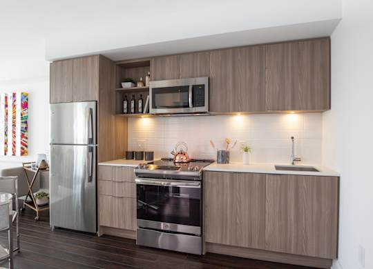 A modern kitchen with a refrigerator, oven, and microwave.