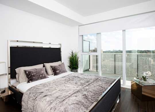 A bedroom with a large bed and a view of the outside through the window.