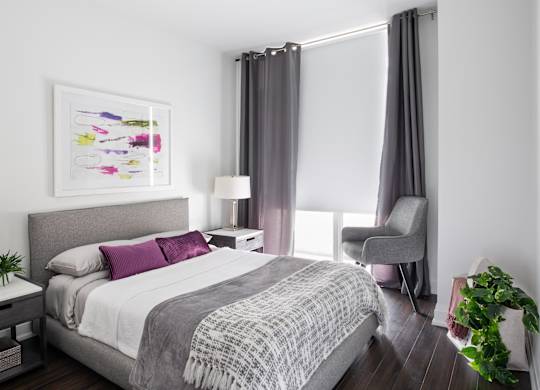 A bedroom with a large bed and a grey chair.