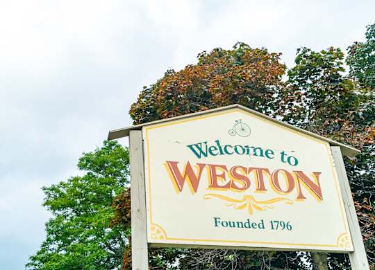 a welcome to weston sign in front of trees