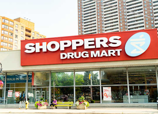a shoppers drug mart store on a city street with tall buildings