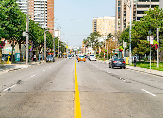 A city street with cars and a yellow line in the middle.