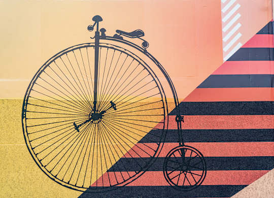 A bicycle is leaning against a wall with a striped pattern.