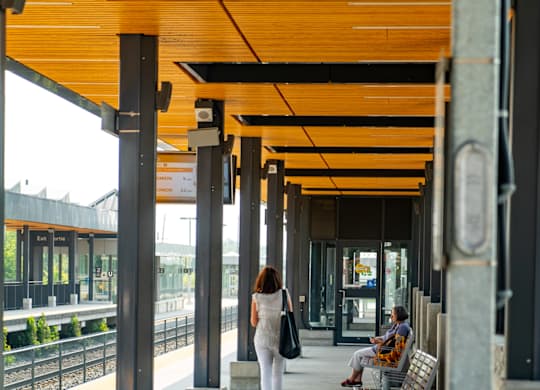 A woman in a white dress is walking on a platform with a train in the background.