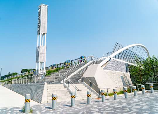 A tall white tower with a sign on it stands next to a set of stairs with a metal railing.