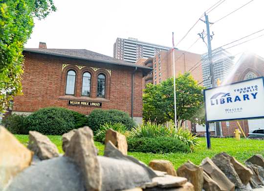 A library sign in front of a brick building.