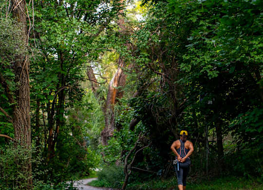 A person is walking on a paved path in a wooded area.
