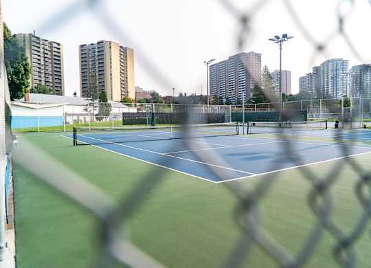 A tennis court is seen through a chain link fence.