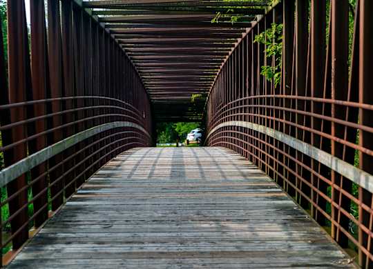 A bridge with a metal railing and wooden planks.