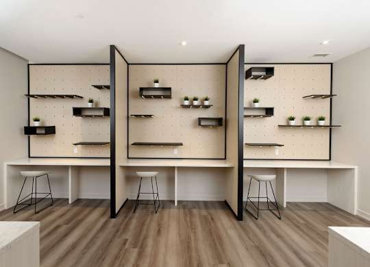 A room with a white table and black stools.