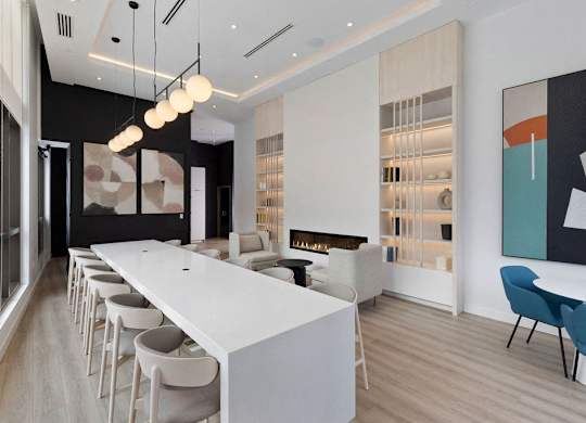 A long white table with chairs on either side is in the middle of a room.