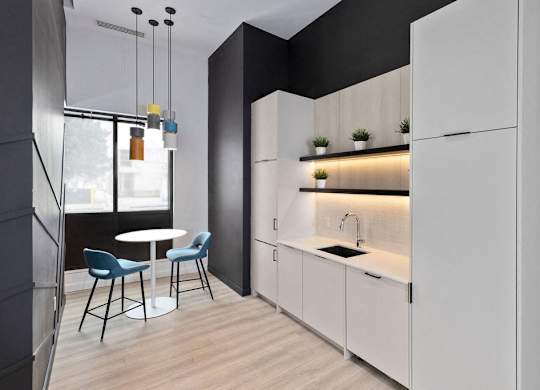 A modern kitchen with white cabinets and a black wall.