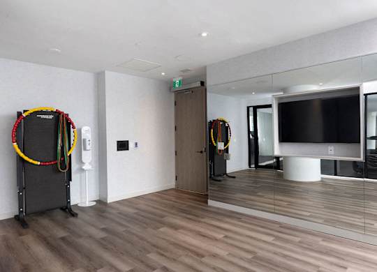 A room with a wooden floor and a black TV on a white stand.