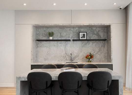 A modern kitchen with a marble backsplash and grey countertop.