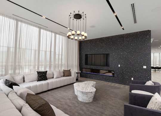 A modern living room with a white sofa, a grey coffee table, and a black and white speckled wall.