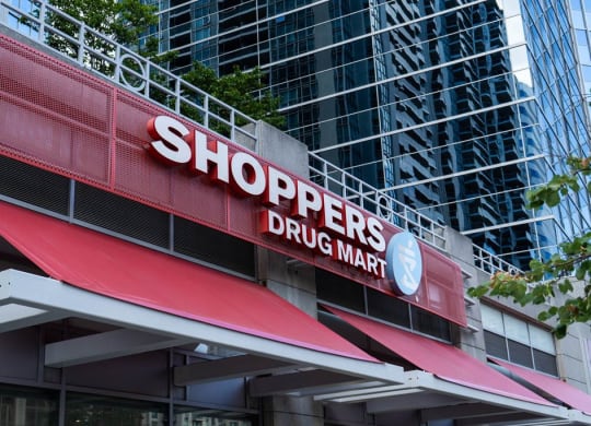 a sign for shoppers drug mart in front of a tall building