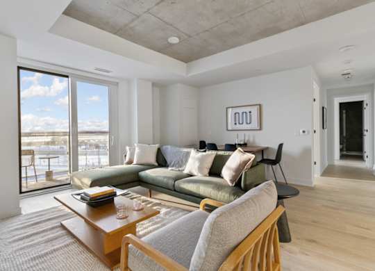 A living room with a couch, a coffee table, and a large window.
